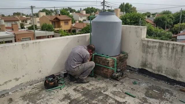 Plomero armando la bajada de termofusión de un tanque de agua con bomba presurizadora en una terraza